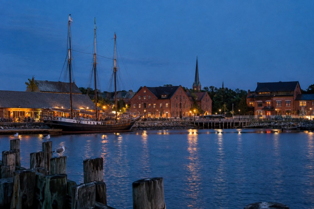 Historic Charlottetown waterfront with brick buildings and masted sailing ships moored along the harbour