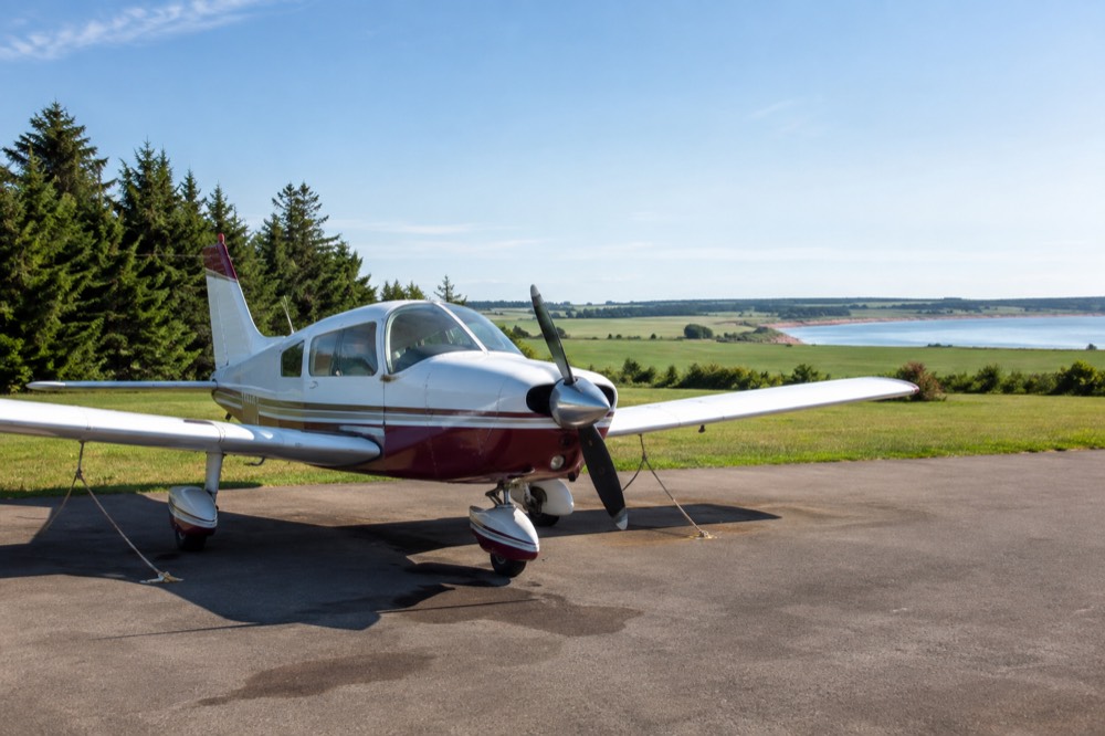 A small aircraft on a runway beside green fields at a maritime island airport