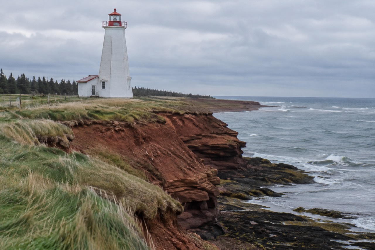 Red sandstone cliffs and a lighthouse along a Prince Edward Island shoreline