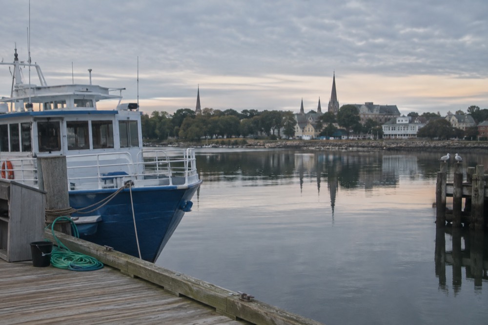 A quiet Charlottetown harbour scene with a tour boat tied up at a wooden dock, low morning light on the water.