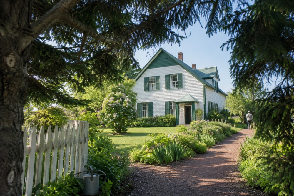 Green gabled farmhouse surrounded by gardens and trees