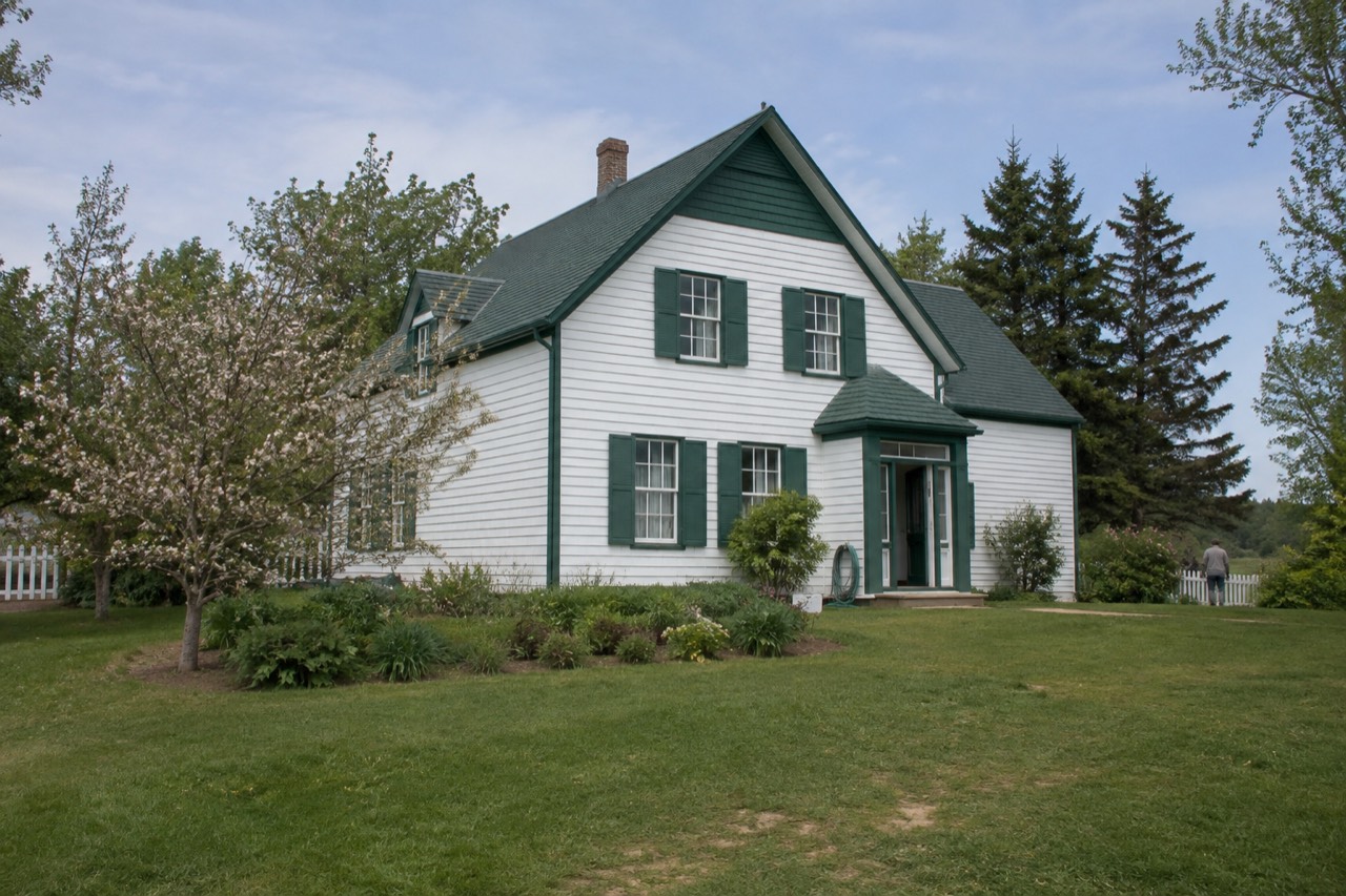 White farmhouse with green gables and trim surrounded by trees at Cavendish on Prince Edward Island