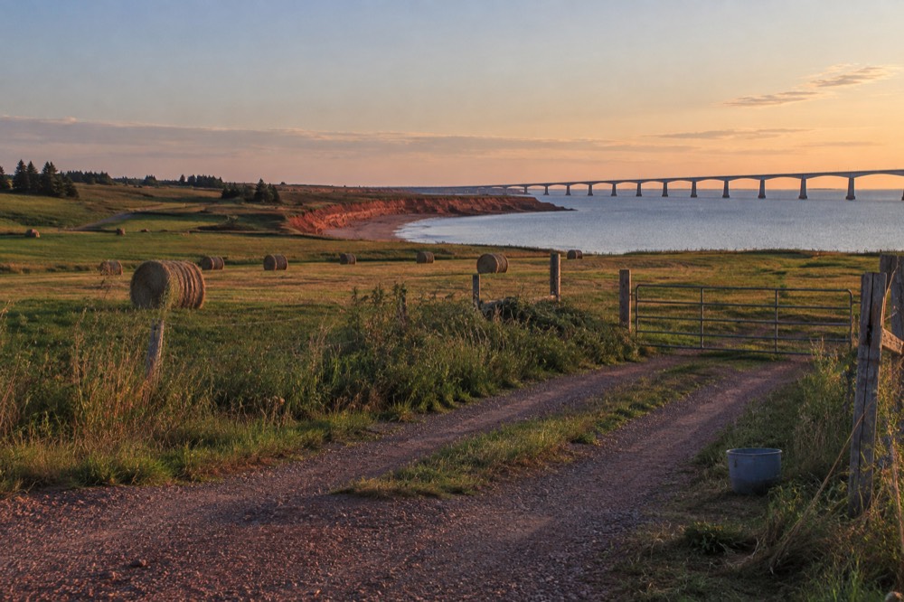 Green farmland meeting the sea along a red cliff shoreline