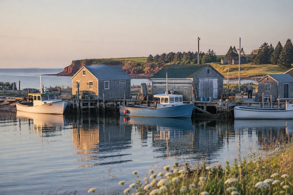 A small harbour village with wooden buildings and fishing boats along a quiet shoreline