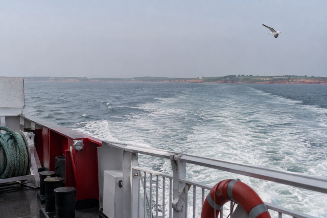 A ferry vessel crossing the blue water of Northumberland Strait toward a green Island shoreline