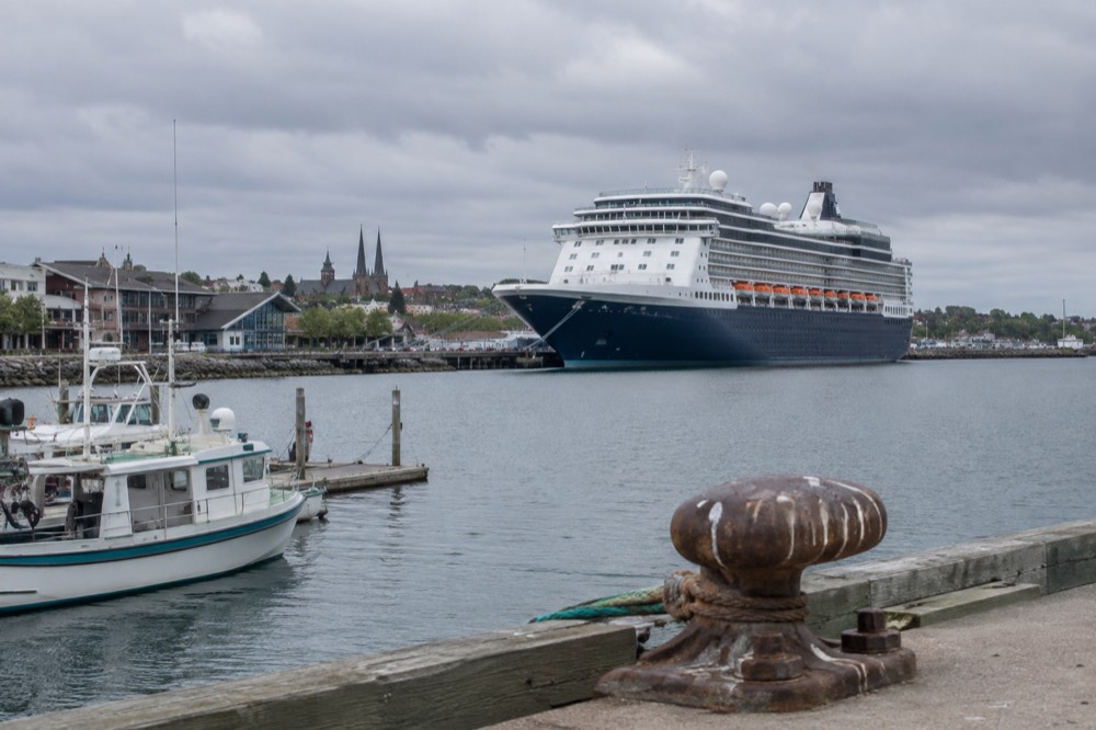 A cruise ship docked at the waterfront in Charlottetown with small boats in the harbour
