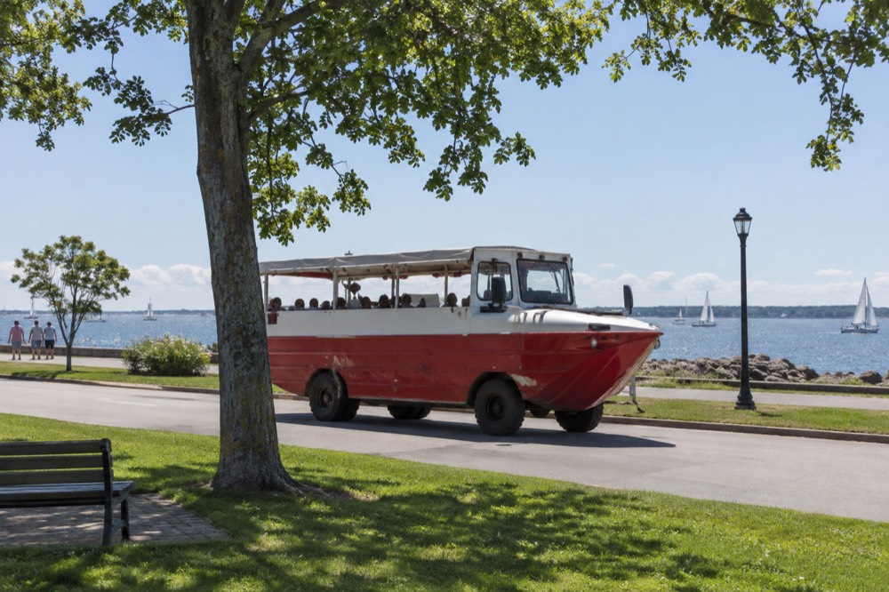 A red-and-white amphibious tour vehicle driving along the Charlottetown waterfront