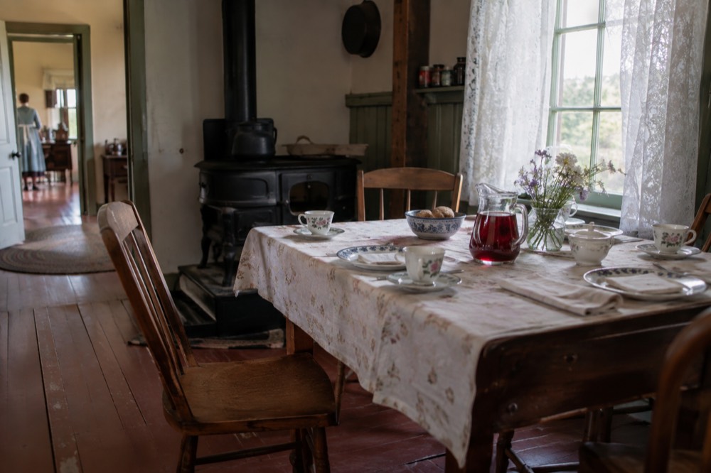 A country kitchen table set with a glass pitcher of red cordial and teacups