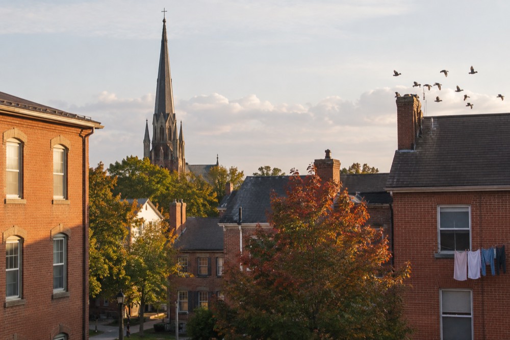 A church spire rising above red brick rooftops in late afternoon light