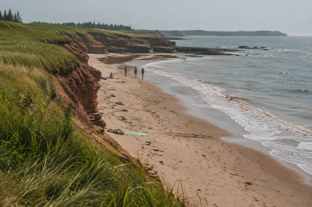 Red sandstone cliffs and a curved sandy beach along the north shore of Prince Edward Island