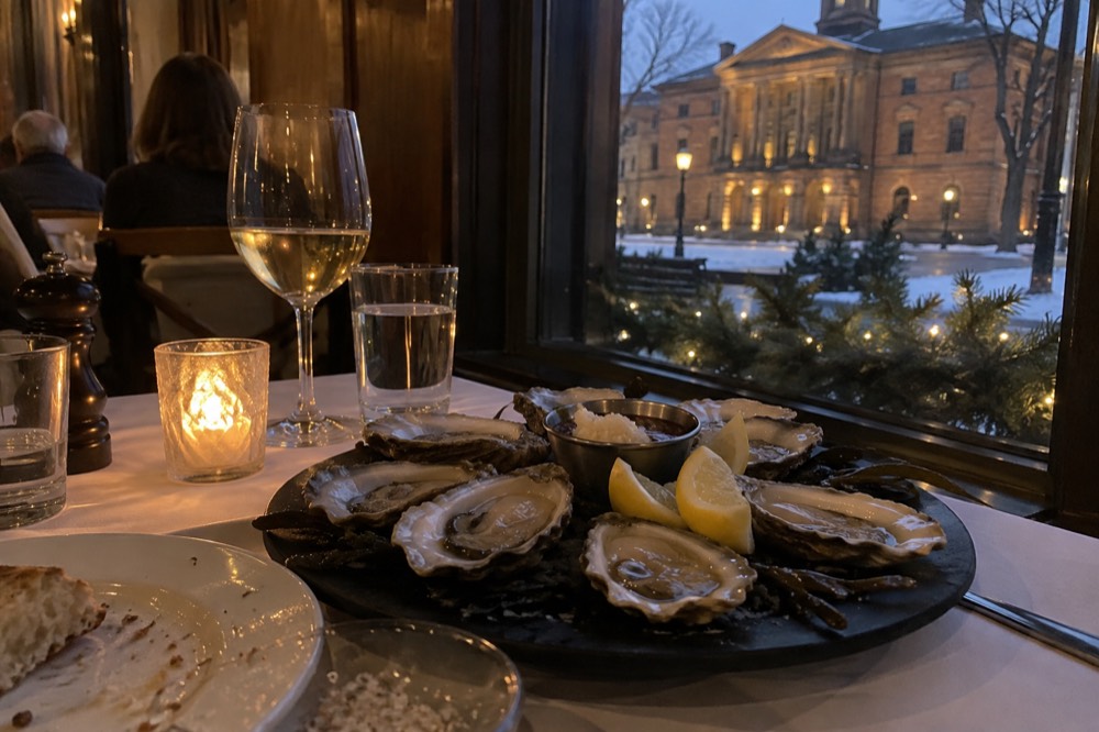 A platter of shucked oysters with lemon wedges on a restaurant table