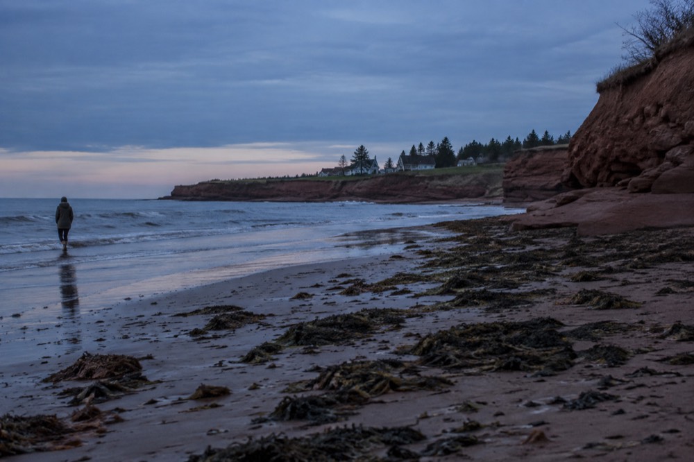 Red sandstone cliffs along a quiet north shore beach at dusk