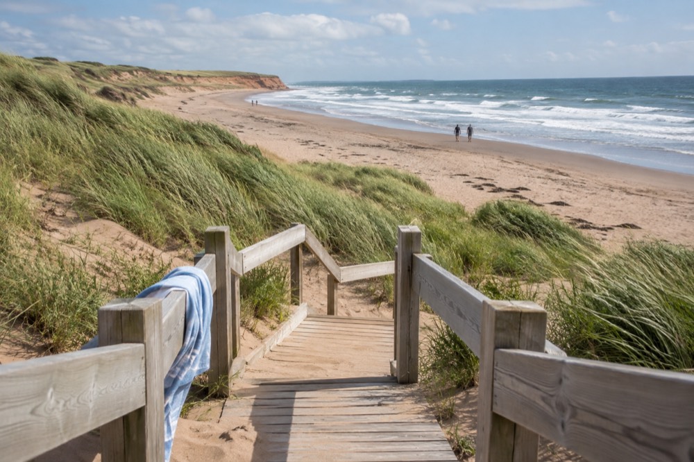 A wooden boardwalk leading over dunes toward a wide sandy beach