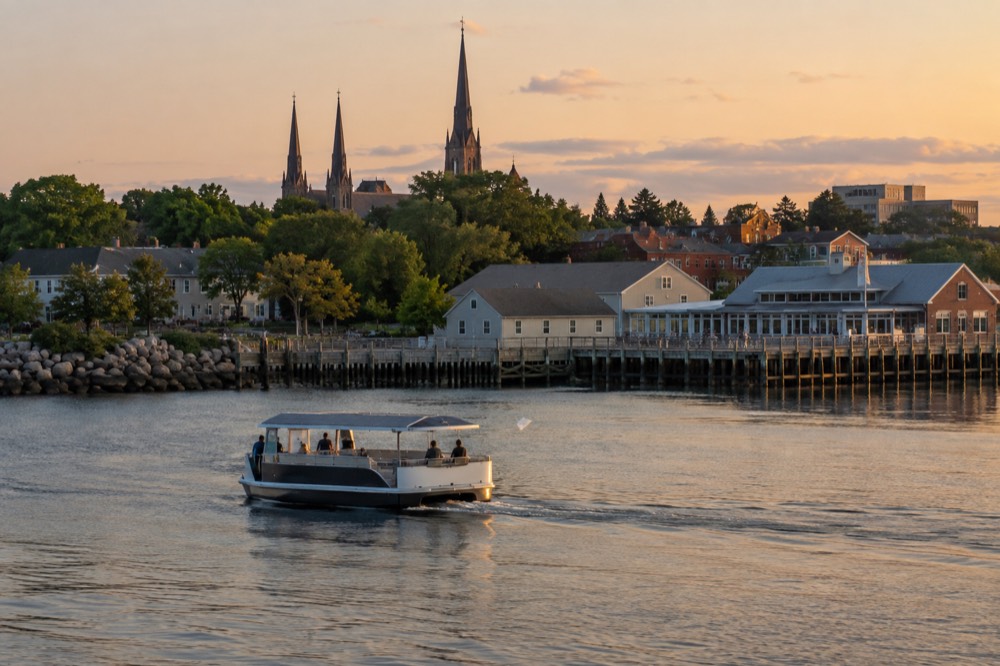 Small solar-powered passenger boat cruising past the Charlottetown harbourfront