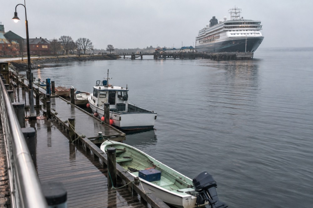 Harbour water with moored small boats and a cruise ship gangway in the distance