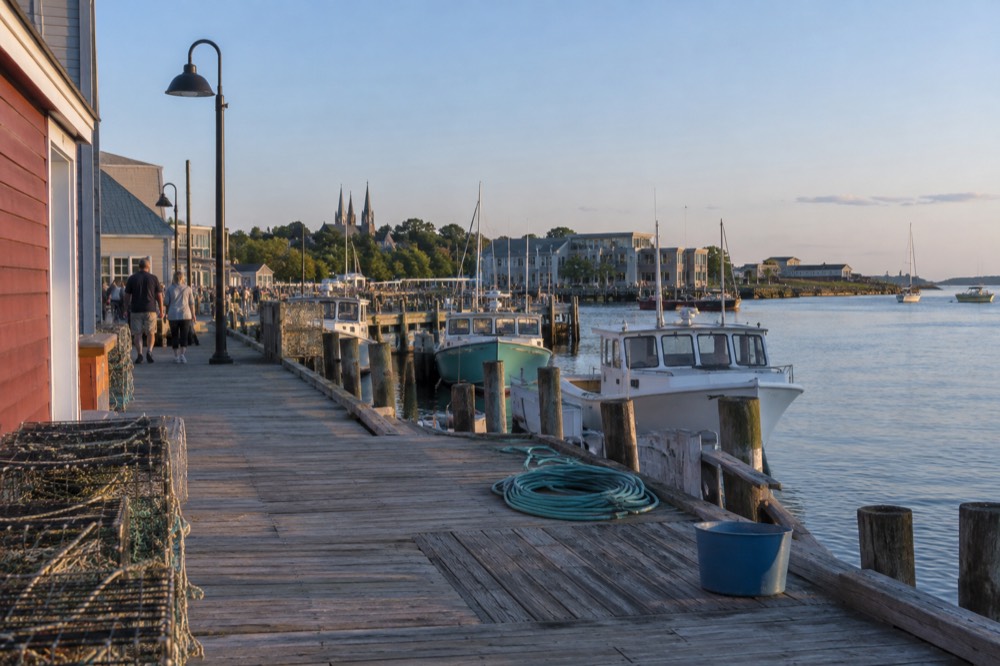 A harbour boardwalk with boats moored beside wooden wharves