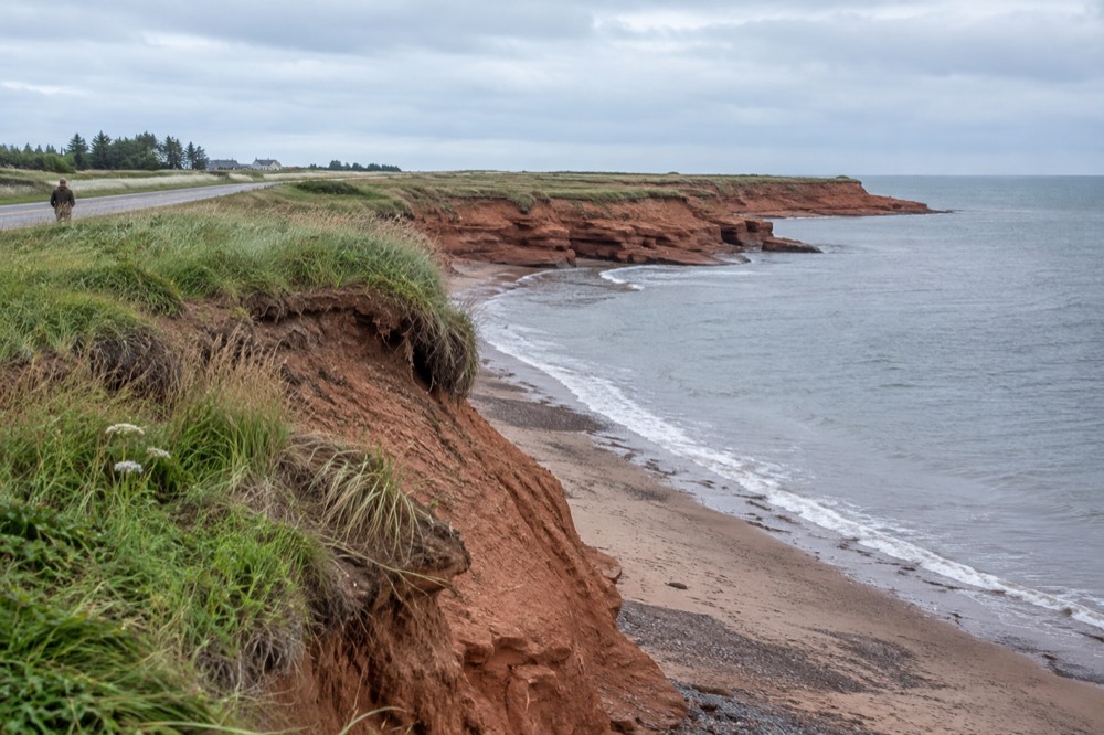 A red sandstone cliff along a quiet island coastal road