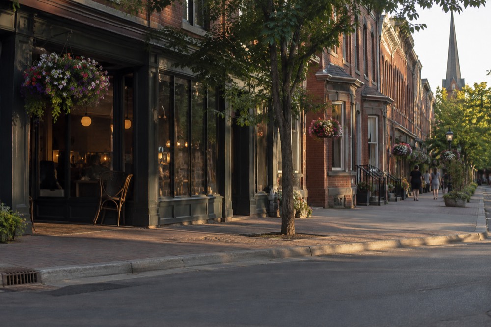 A harbour town street with brick storefronts and hanging flower baskets