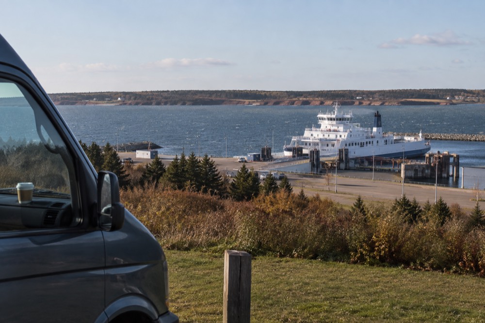 A small tour van parked beside a coastal viewpoint