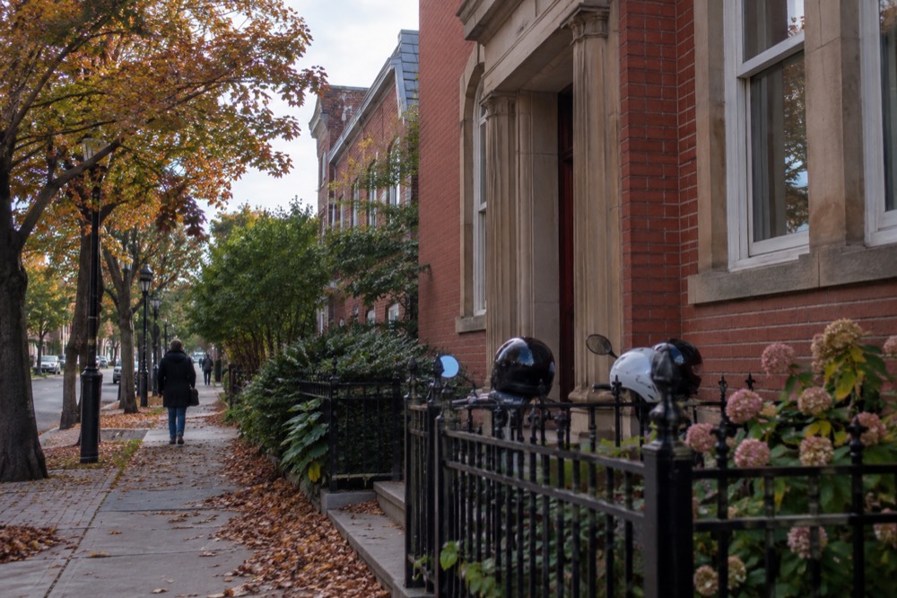 A row of electric bicycles parked beside a historic brick street corner