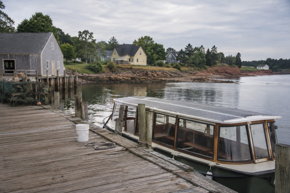Solar-powered tour boat moored at a wooden wharf in a small harbour