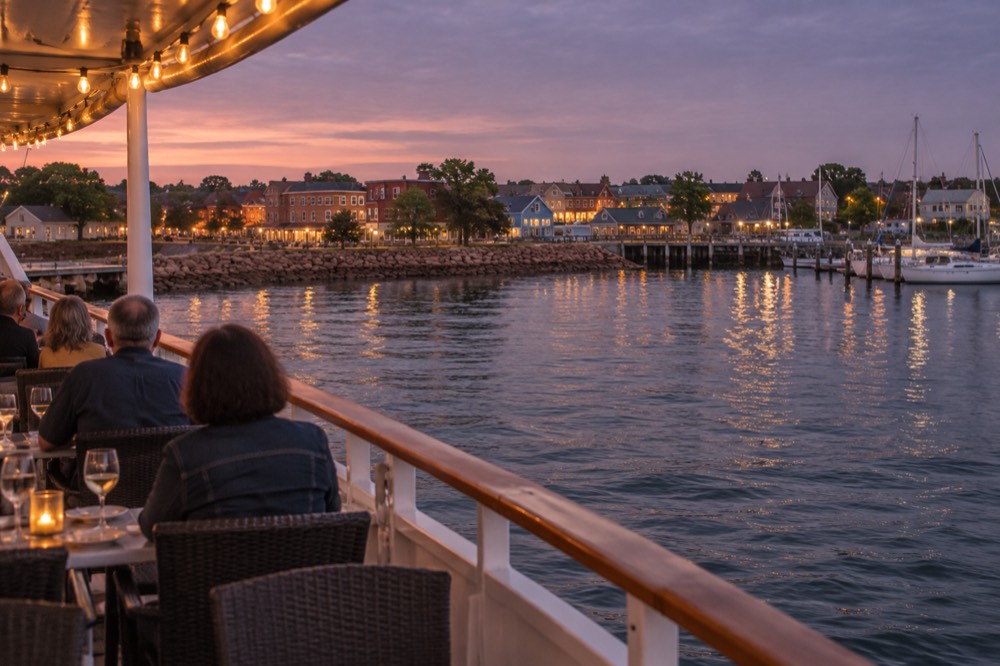 Dinner cruise boat at dusk with warm lights along its deck