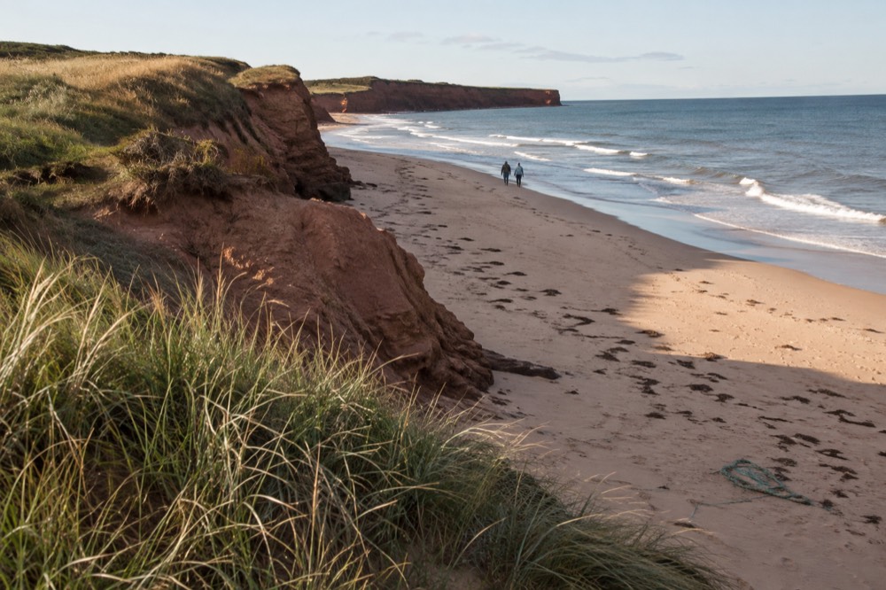 Red sandstone cliffs dropping to a pale sand beach below