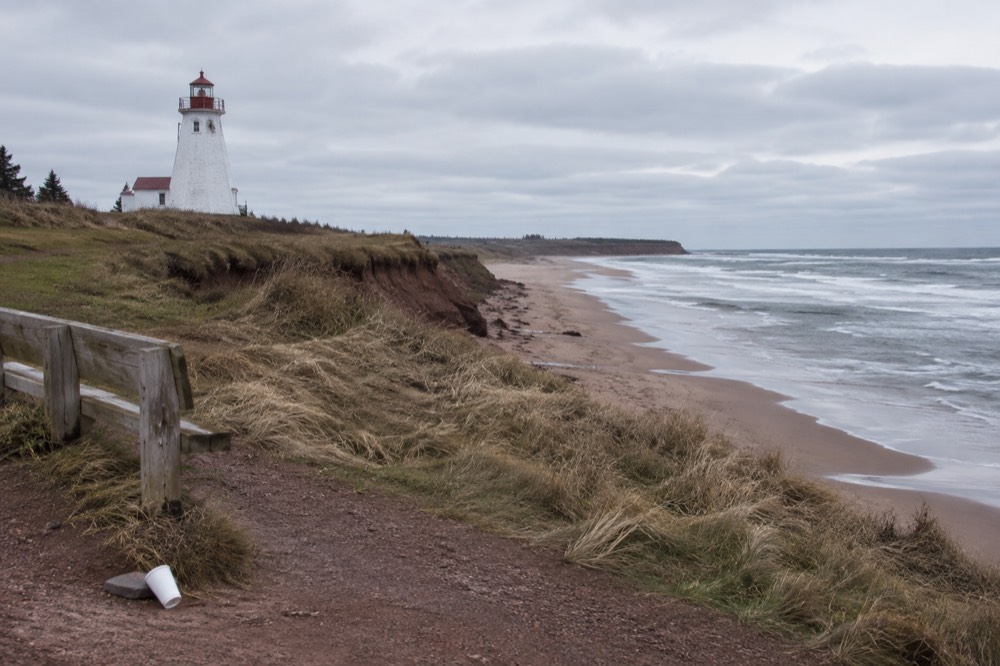 An empty scenic overlook above a wide beach under a grey sky