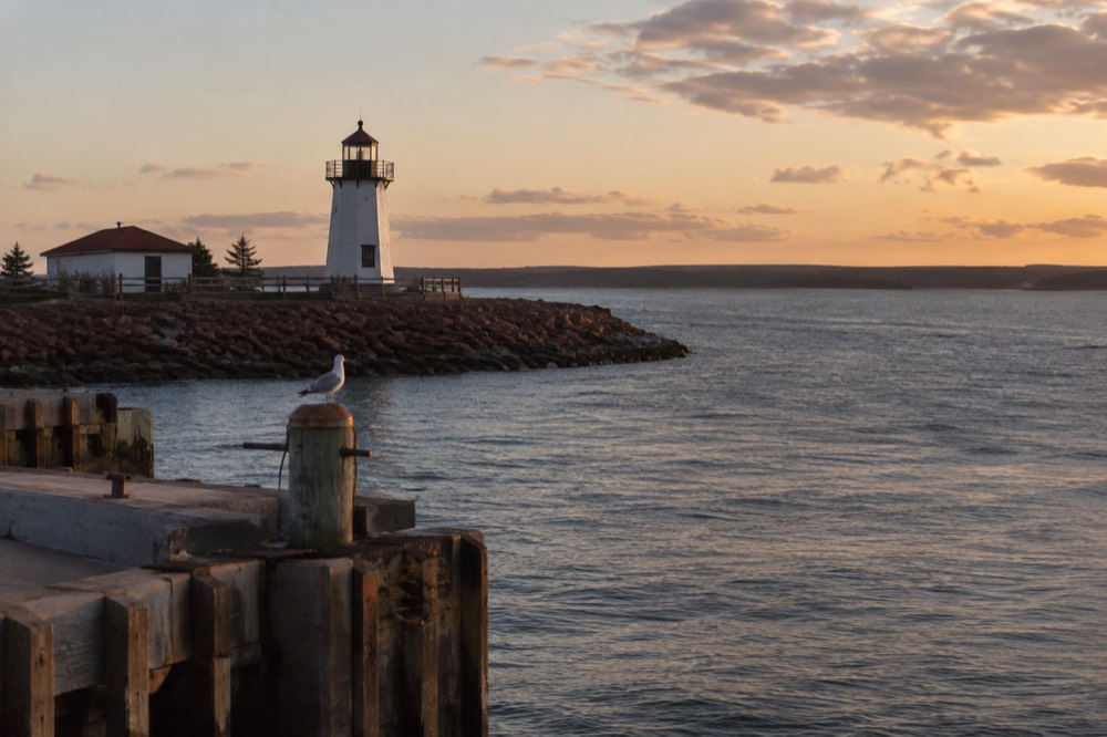 A lighthouse tower against a late afternoon sky over calm water