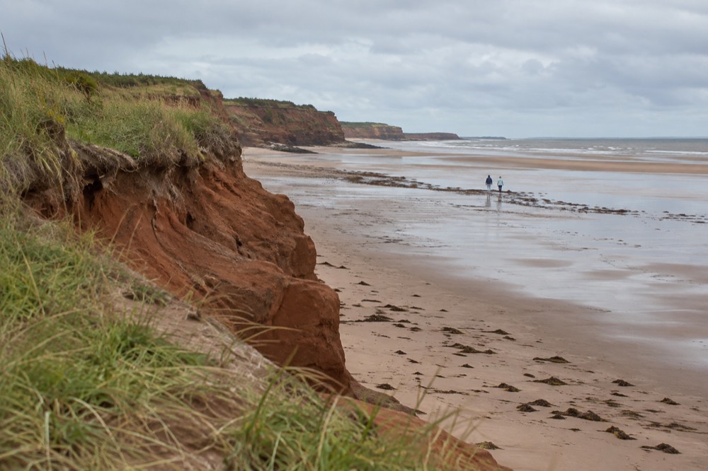 A red sandstone cliff above a calm beach on the north shore