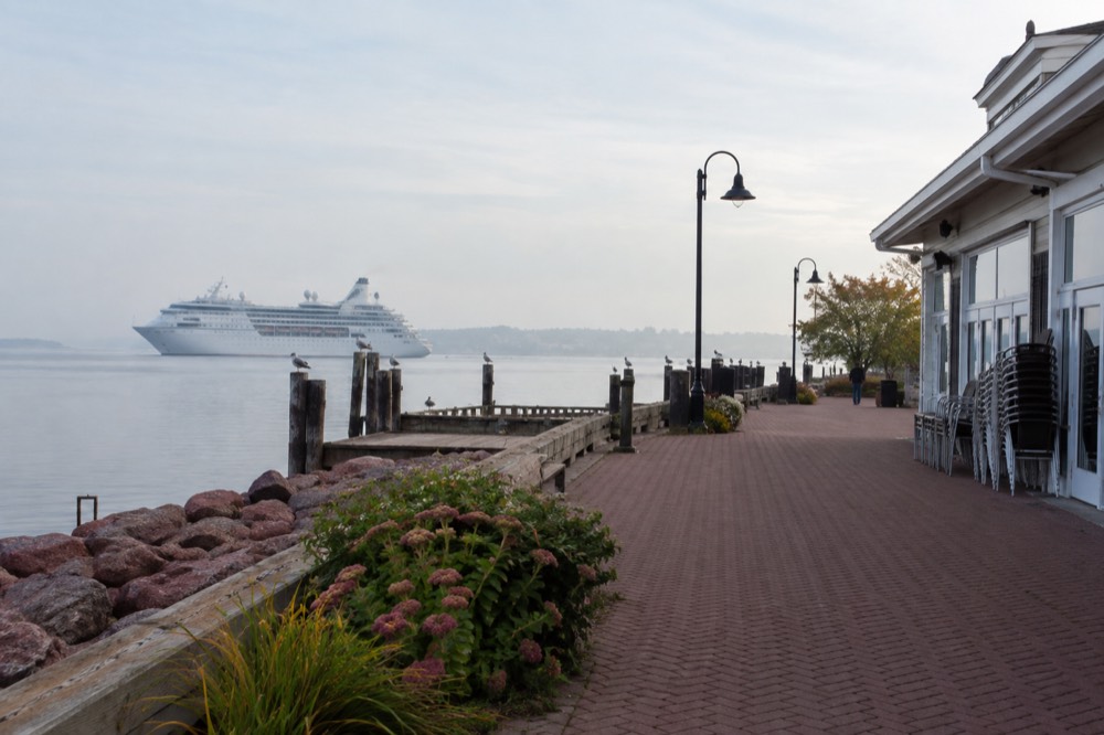 A cruise ship at anchor beyond a harbourfront boardwalk
