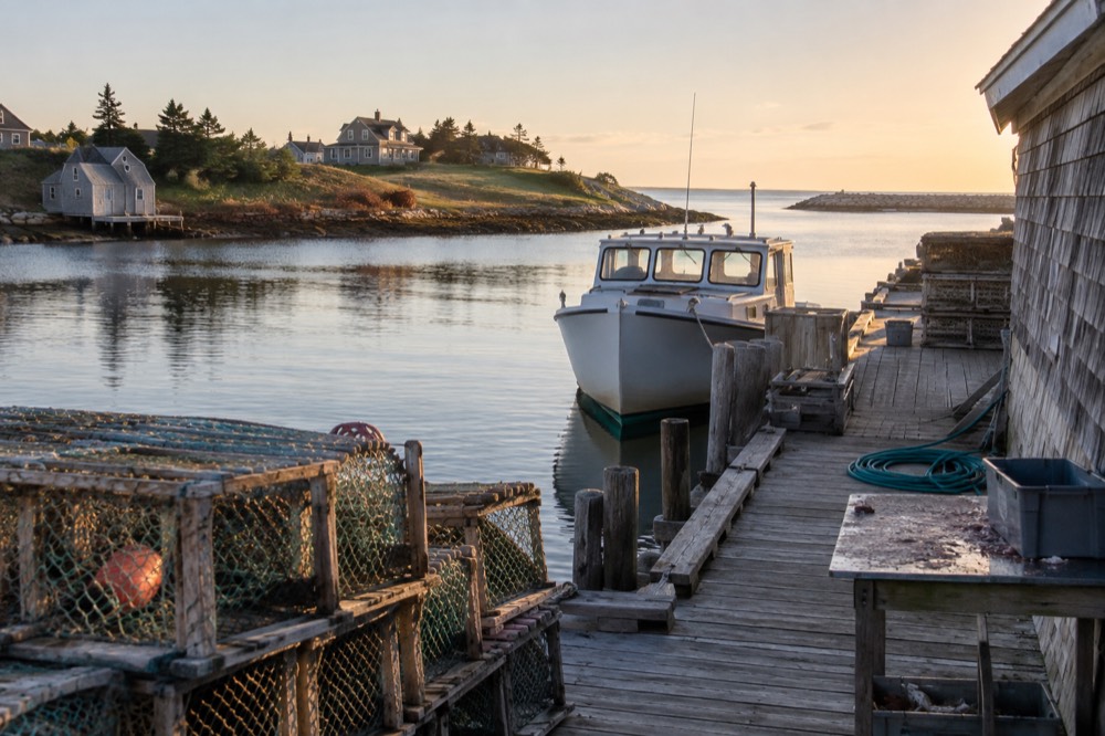 A small tour boat tied up at a wooden wharf in a quiet Island harbour