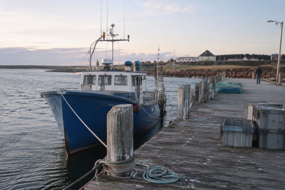 A lobster boat tied up at a wooden wharf in a small Island harbour