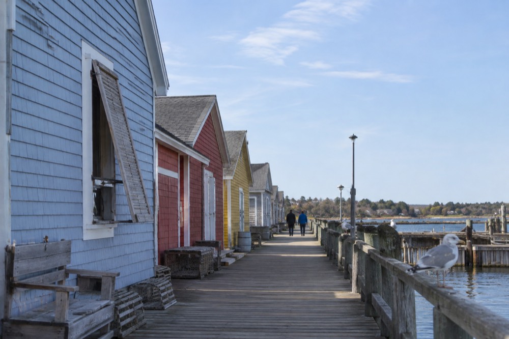 A flat waterfront boardwalk beside a row of colourful historic buildings