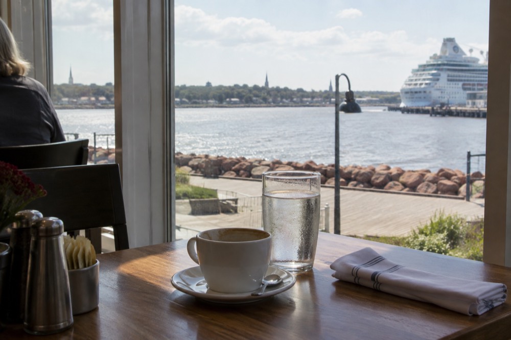 A table set for lunch beside a window overlooking a harbour