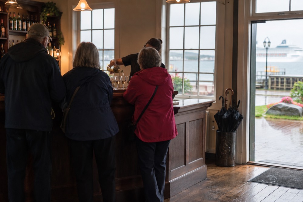 A small group standing at a bar counter while a guide pours samples