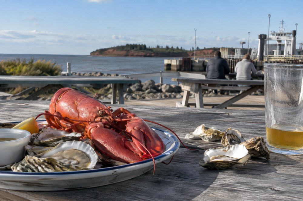 Fresh lobster and oysters plated on a wooden dockside table