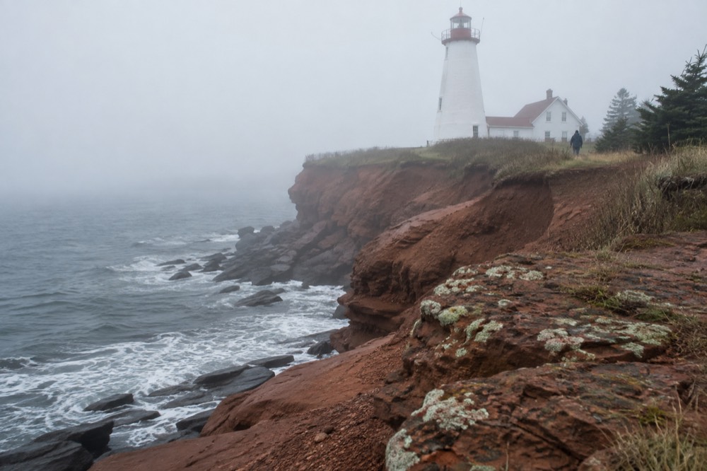 White lighthouse on a red cliff above the sea